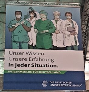 Foto eines Werbeplakates mit fünf in der Medizin tätigen Personen und dem Titel "Unser Wissen. Unsere Erfahrung. In jeder Situation."