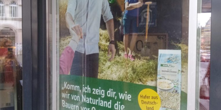 Bild eines Werbeplakates von Naturland mit einem Mann und einer Frau auf einem Feld. von