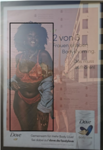 Werbeplakat mit Planimetrielinien von Dove mit dem Titel "2 von 3 Frauen erleben Bodyshaming" und einer dunkelhäuftigen, schwarzhaarigen Frau.