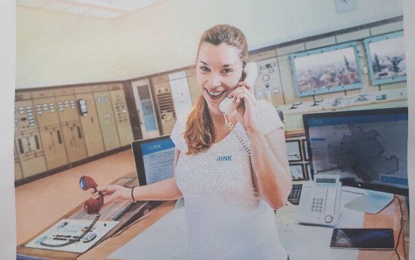 Bild einer jungen Frau mit einem Telefonhörer am Ohr.