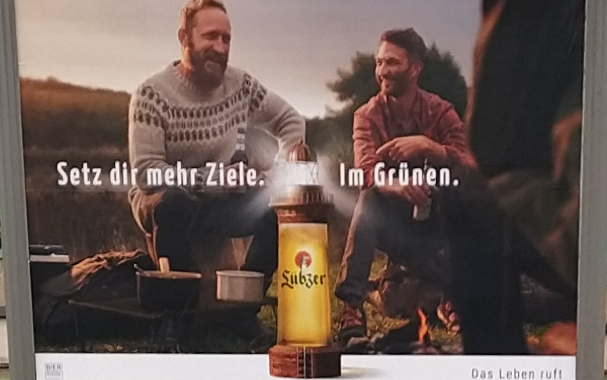 Werbeplakat für das Bier Lübzer mit drei Männern in der Natur