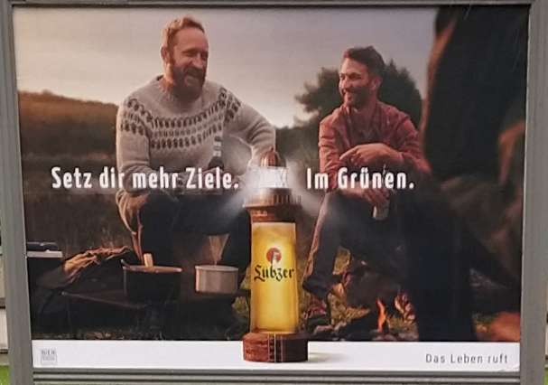Werbeplakat für das Bier Lübzer mit drei Männern in der Natur