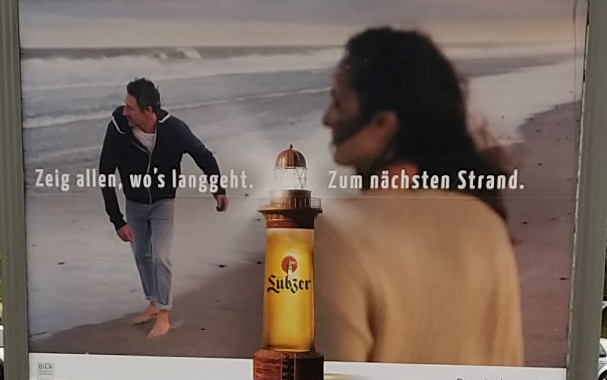 Werbeplakat der Biermarke "Lübzer" mit einer Frau und einen Mann am Strand